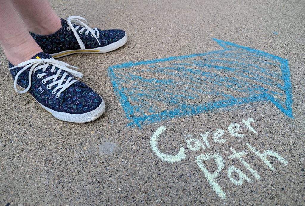 person standing beside a chalk drawing of an arrow with caption Career Path